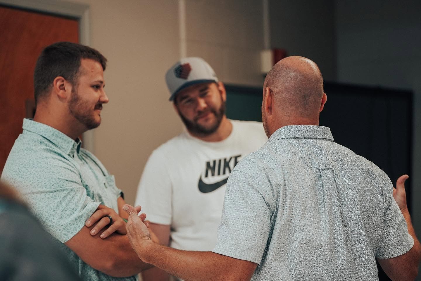 Three people in casual short-sleeved shirts talking together after a service